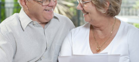 Elderly couple talking and smiling looking at a document